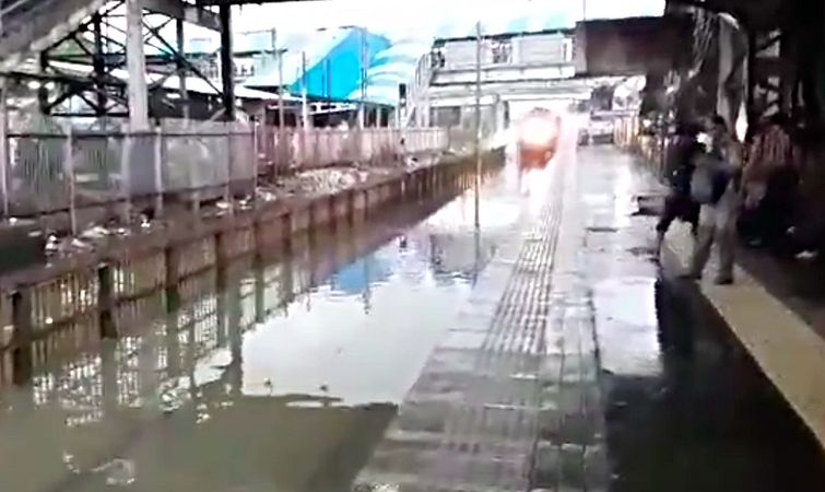 Поезд проехал по затопленной станции, поезд обрызгал пассажиров, поезд забрызгал пассажиров