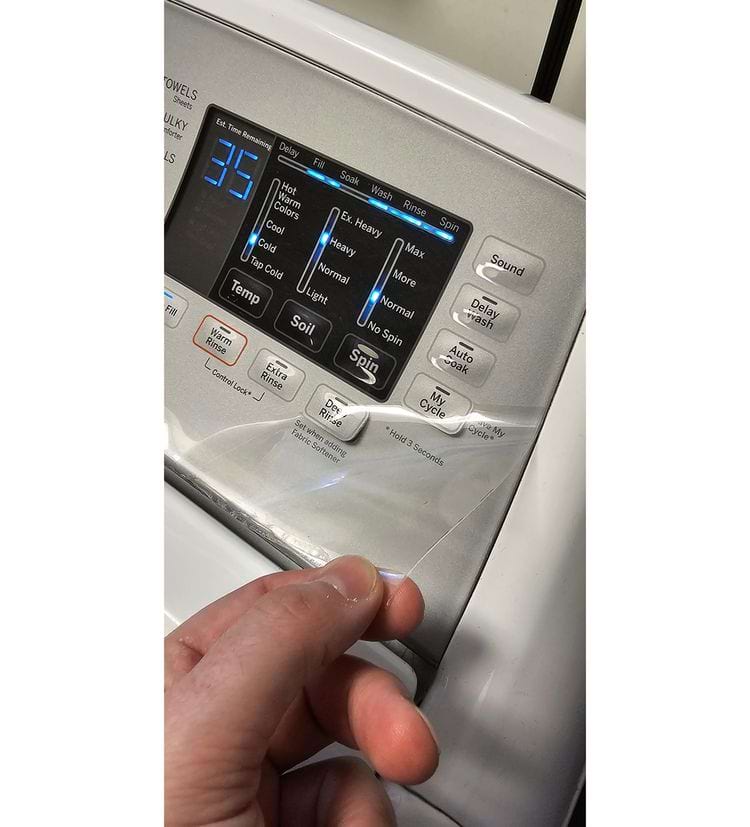 мужчина снимает плёнку с табло стиральной машины