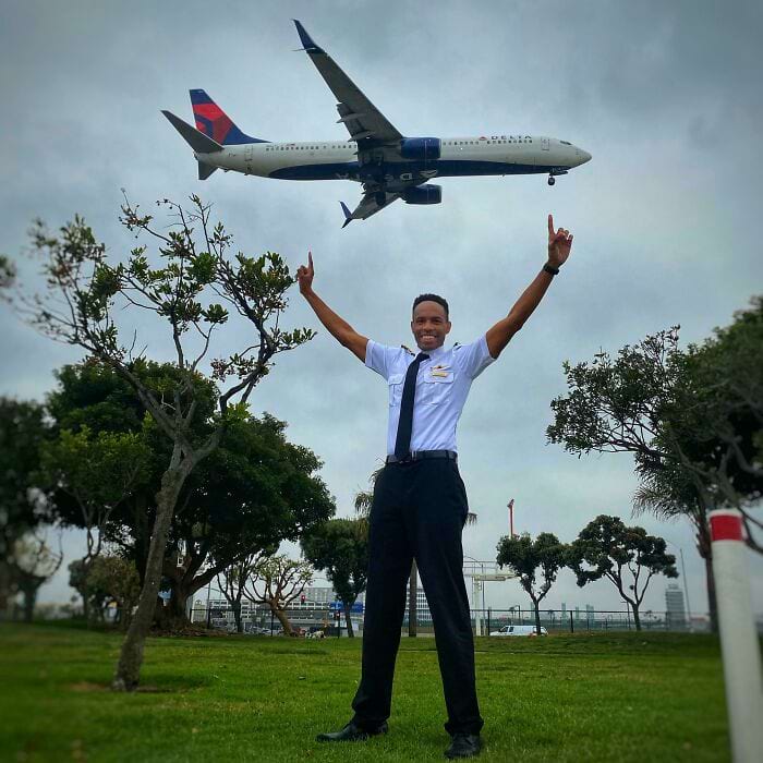 пилот показывает пальцами на пролетающий мимо самолёт