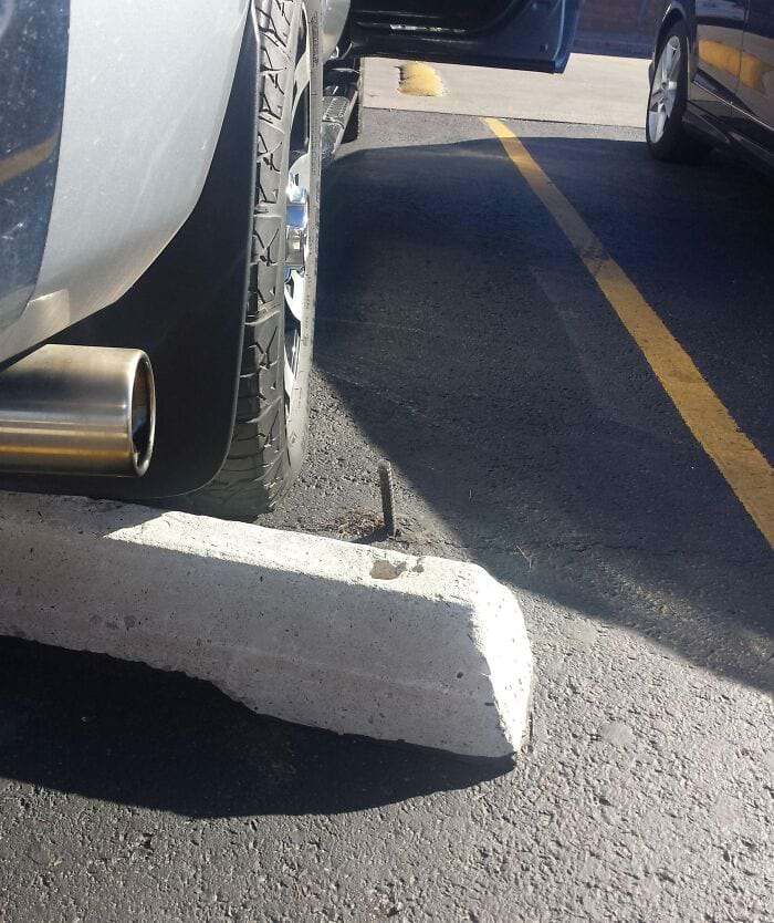 автомобиль припаркован рядом со штырём, торчащим из асфальта