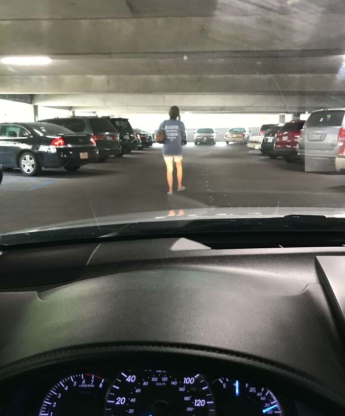 женщина идёт перед машиной на парковке