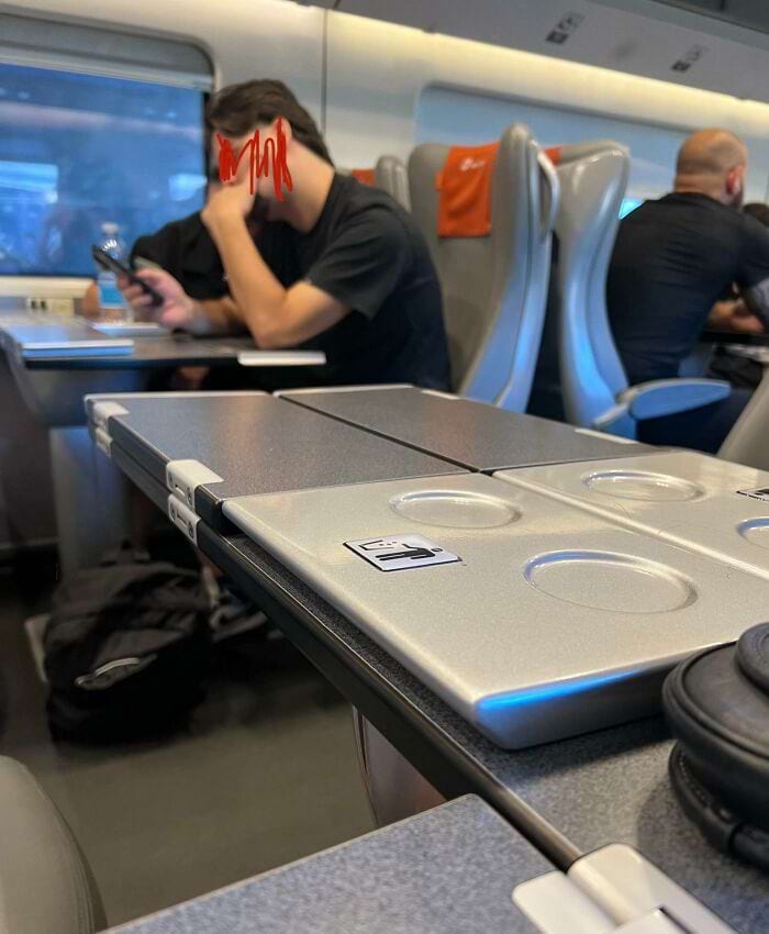 люди сиядт на стлом в поезде и смотрят в телефон