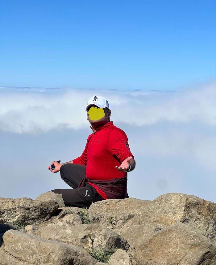 мужчина сдит на горе и развёл руки