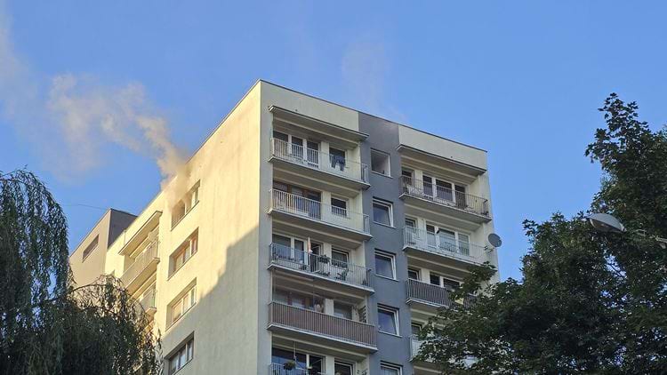 из окна верхнего этажа дома идет дым