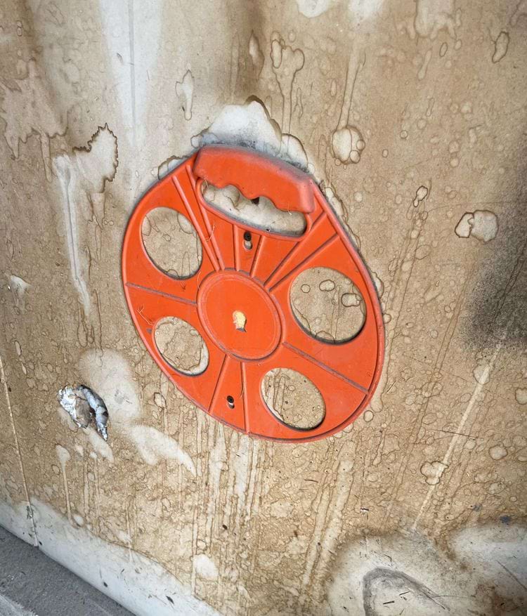 старая катушка с переноской, которую кто-то прикрепил к стене и которая сломалась пополам