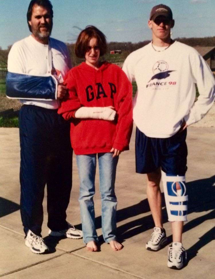 семья стоит с гипсом и шинами на руках и ногах